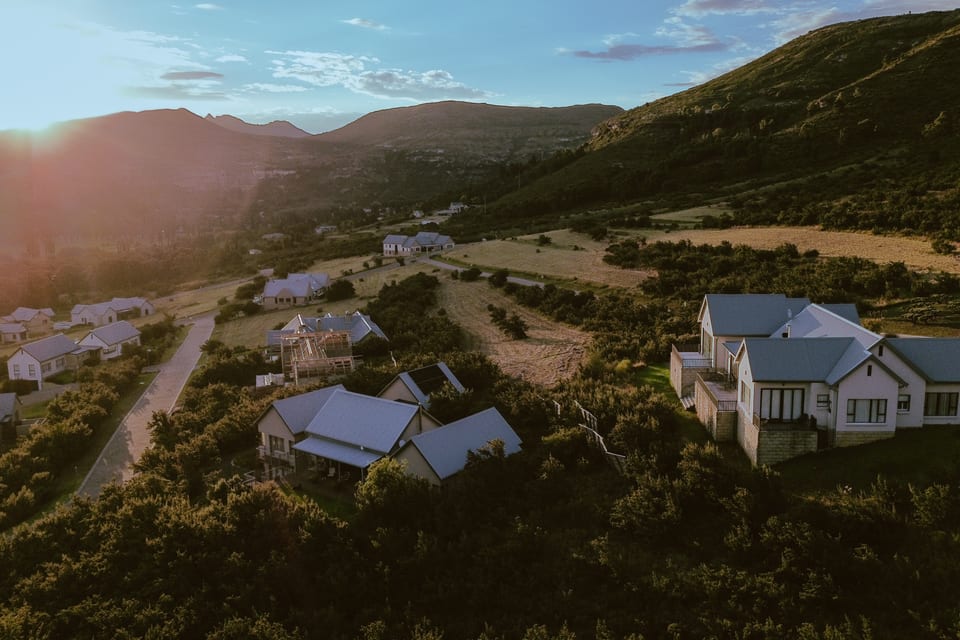 Aerial view over homes at Clarens Mountain Estate in low evening sun, with the ridge behind