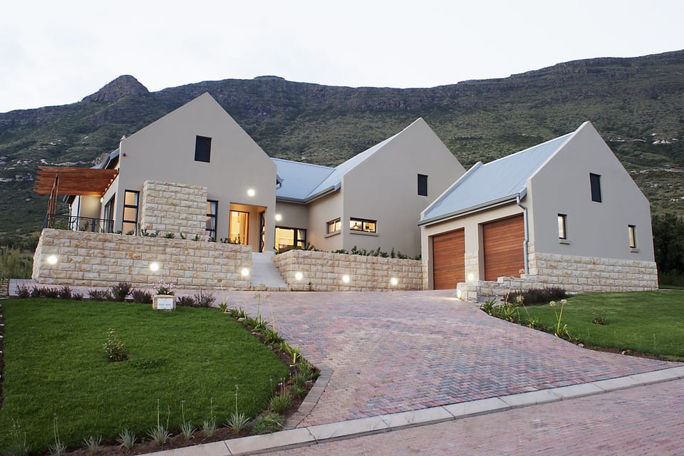 A gabled estate home at dusk with warm light in the windows