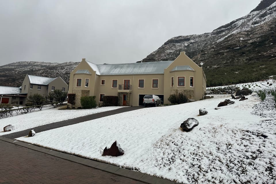 An estate home under snow, with the mountain white behind it