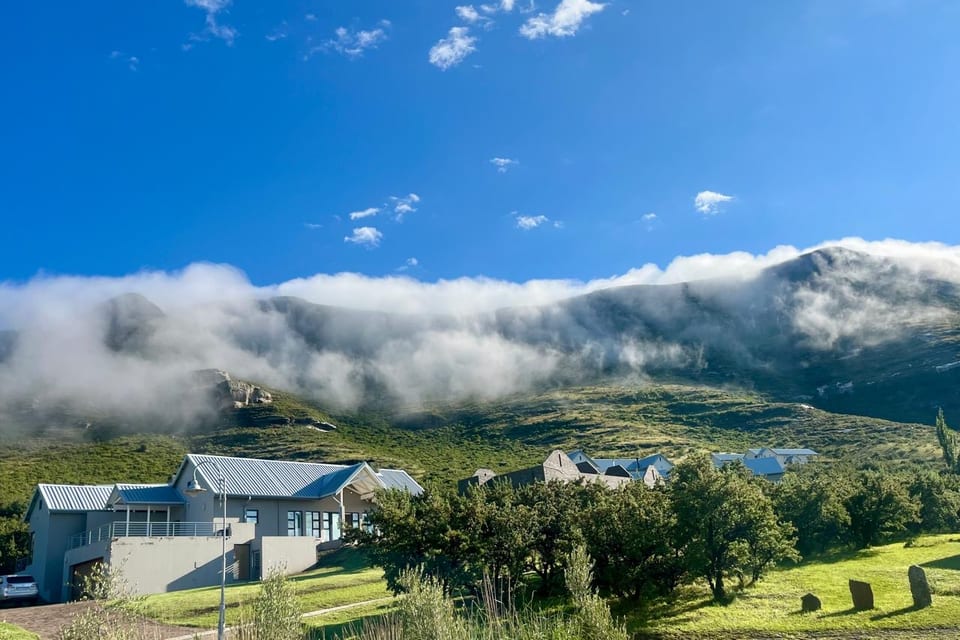 Estate homes with low cloud spilling over the mountain ridge