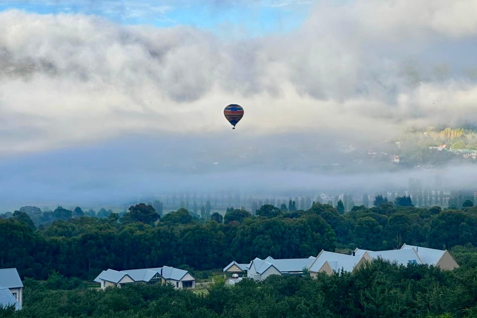 A hot-air balloon drifting over the misty valley at dawn