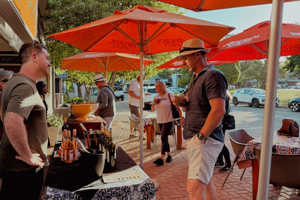Visitors gathered under red umbrellas at an outdoor market in Clarens